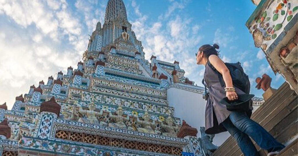 a woman looks up at a temple in bangkok