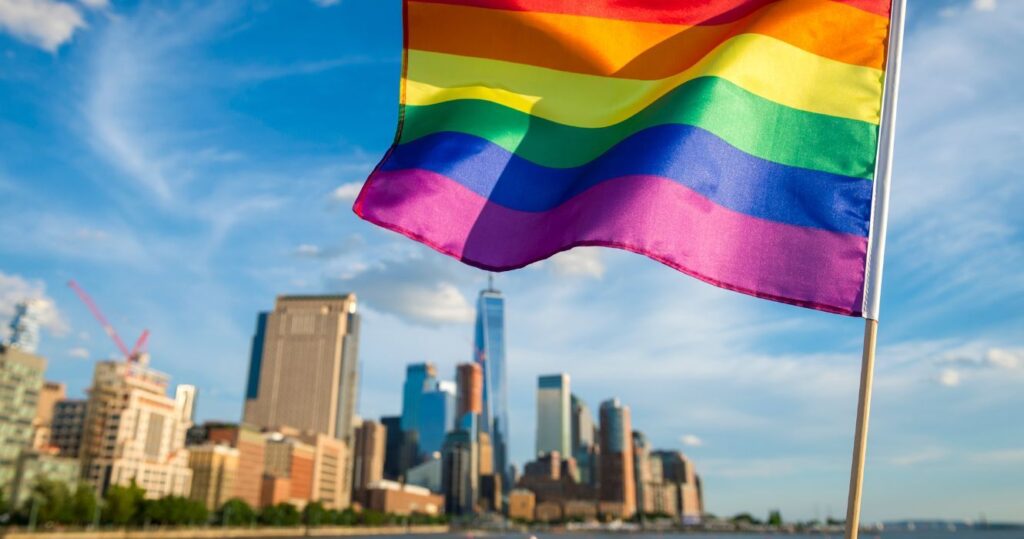 the pride flag waving with the NYC skyline in the background